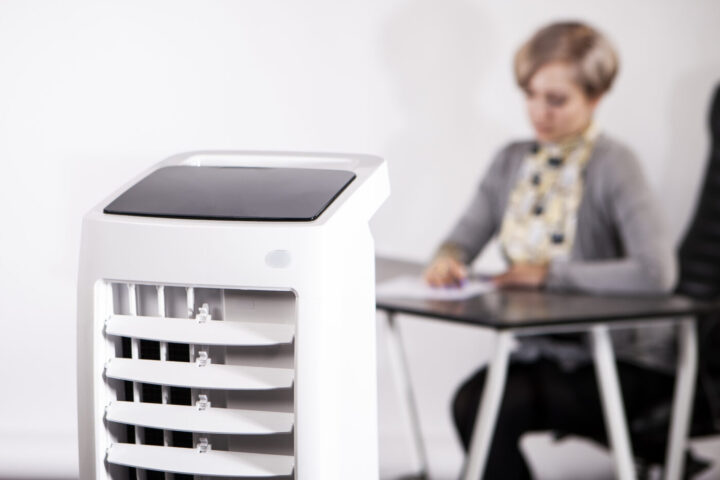 Air purifier in the office. A woman works in an office with air conditioning. Caring for employees. Air conditioning facilities. Outdoor air conditioning.