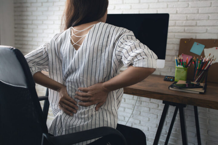 Business woman suffering from back pain in office
