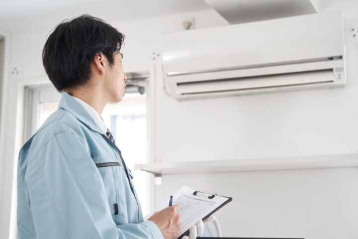 家庭用エアコンのチェックをする日本人男性電気工事士