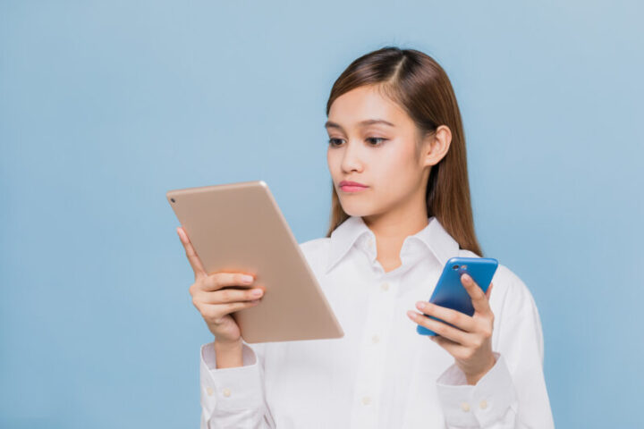 Young woman holding two smart phones.