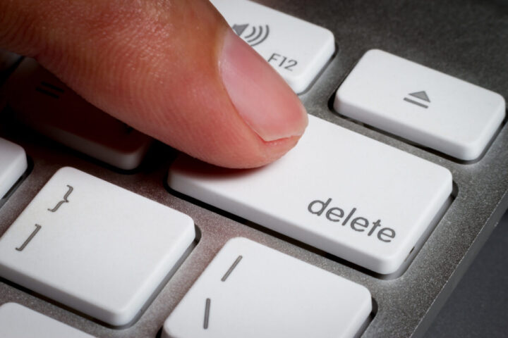 Closeup of finger on delete key in a keyboard.