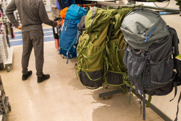 A man chooses a large hiking backpack for travel in a shopping mall